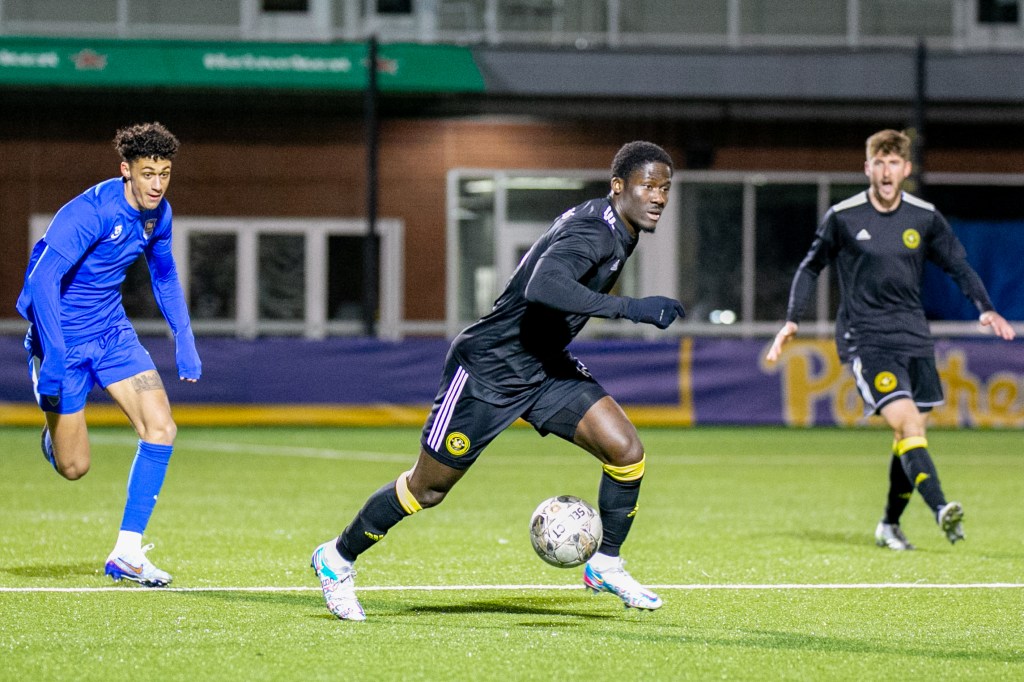 DZ Harmon possesses the ball between two players - Pittsburgh Riverhounds SC
