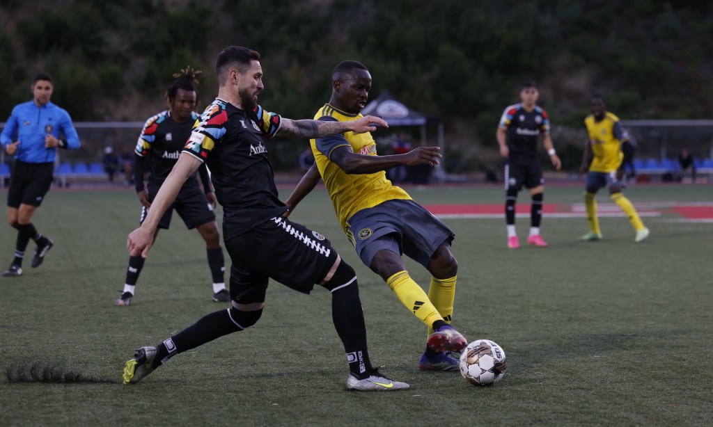 Edward Kizza gets a pass away under pressure during the Riverhounds' 0-0 draw at Oakland Roots SC on June 17, 2023 at Pioneer Stadium in Heyward, Calif.