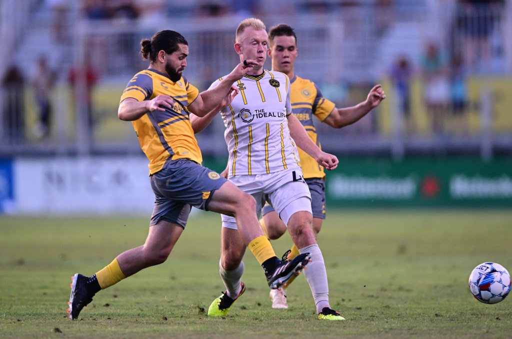 Riverhounds players Jackson Walti and Robbie Mertz converge on the Charleston Battery's Chris Allan in the teams' 0-0 draw on June 8, 2024 at Patriots Point Soccer Complex in Mount Pleasant, South Carolina - Pittsburgh Riverhounds SC