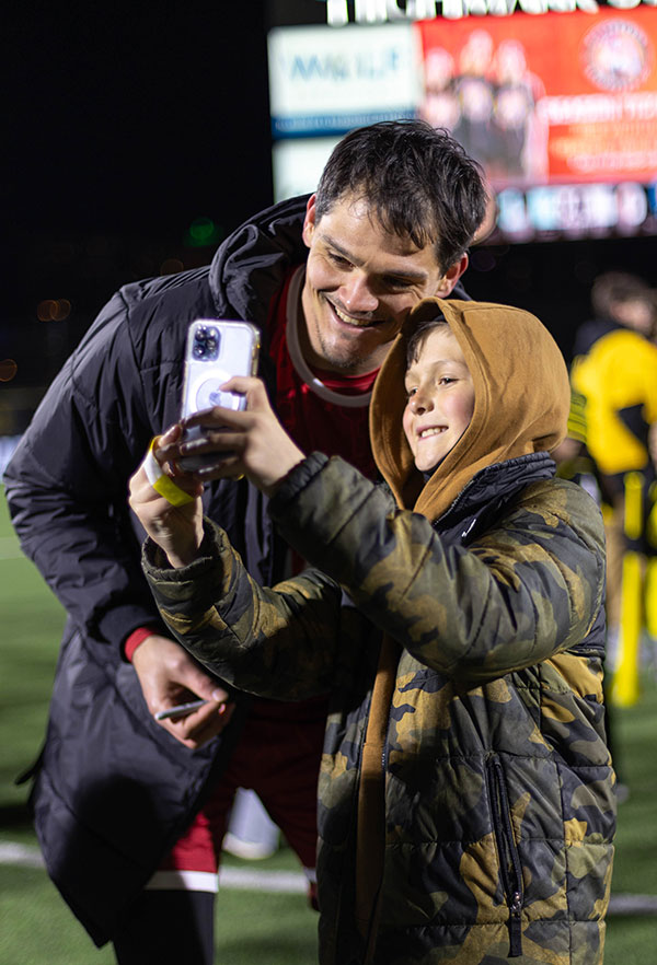 Riverhounds goalkeeper Eric Dick takes a selfie with a young fan after a home match