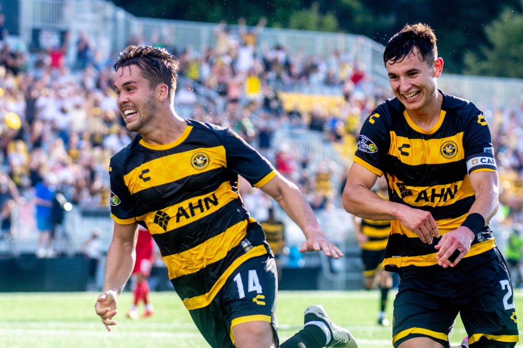 Pittsburgh Riverhounds midfielder Robbie Mertz is joined by teammate Danny Griffin as he celebrates scoring a goal in the team's 2-2 draw against Loudoun United FC on July 13, 2025 at Highmark Stadium in Pittsburgh. (Photo: Chris Cowger/Riverhounds SC)