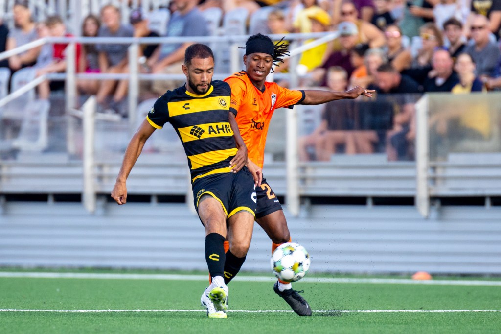 Pittsburgh Riverhounds defender Guillaume Vacter is first to the ball in front of Orange County SC's Mouhamadou War in the teams' 1-1 draw Aug. 9, 2025 at Highmark Stadium in Pittsburgh. (Photo: Chris Cowger/Riverhounds SC)