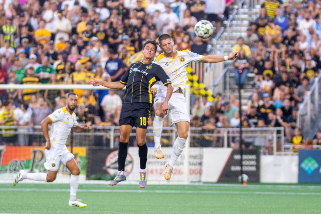 The Pittsburgh Riverhounds' Luke Biasi (right) jumps to win the ball against the Charleston Battery's Arturo Rodriguez in the teams' match Aug. 16, 2025 at Highmark Stadium. (Photo: Chris Cowger/Riverhounds SC)