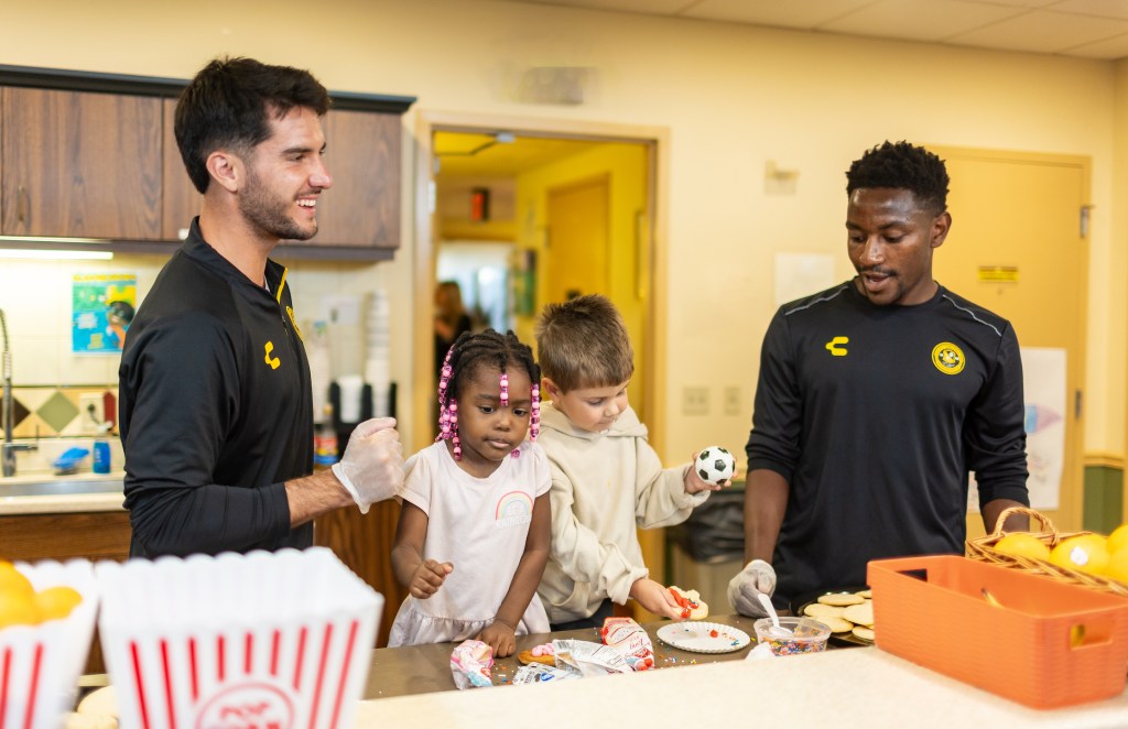 Pittsburgh Riverhounds players Beto Ydrach (left) and Perrin Barnes (right) help to prepare cookies with area children at Ronald McDonald House Pittsburgh in the city's Lawrencevile neighborhood. (Photo: Mallory Neil/Riverhounds SC)