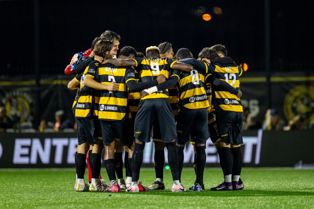 Pittsburgh Riverhounds players huddle before their playoff win against Detroit City FC on Nov. 8, 2025 at Highmark Stadium in Pittsburgh. (Photo: Chris Cowger/Riverhounds SC)