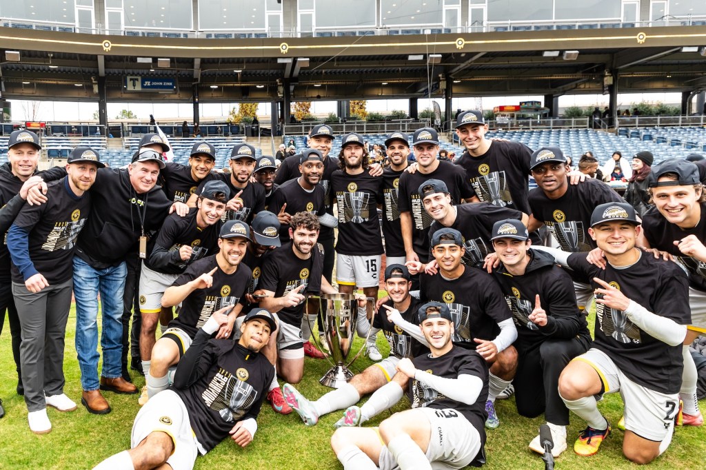 Pittsburgh Riverhounds players hold the USL Championship trophy after winning the title on penalty kicks over FC Tulsa on Nov. 22, 2025 at ONEOK Field in Tulsa, Okla. (Photo: Mallory Neil/Riverhounds SC)
