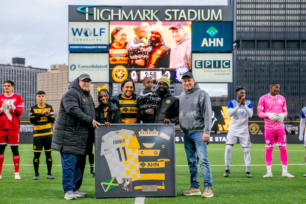 Longtime Pittsburgh Riverhounds star Kenardo Forbes is joined on the field at Highmark Stadium by his family, team owner Tuffy Shallenberger and head coach Bob Lilley prior to the team's match on March 22, 2025. (Photo: Chris Cowger/Riverhounds SC)