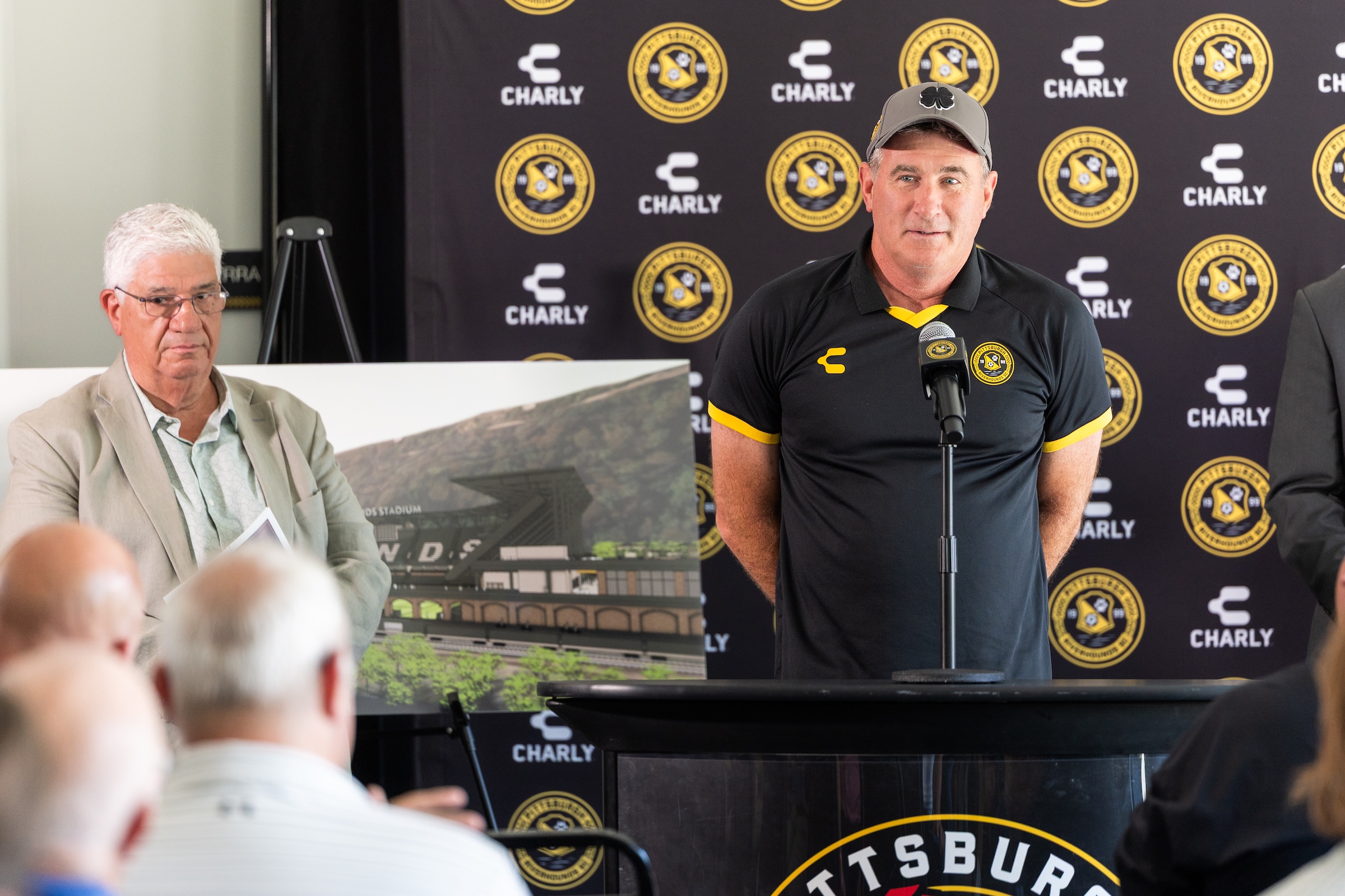 Pittsburgh Riverhounds SC owner Tuffy Shallenberger speaks about the Highmark Stadium expansion plan, flanked by Pa. Senator Wayne Fontana and one of the renderings of the proposed expansion. (Photo: Ryan Shaffer/Riverhounds SC)
