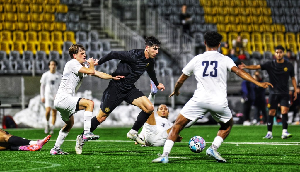 Pittsburgh Riverhounds forward Trevor Amann moves the ball between a pair of Duquesne University defenders in the Hounds' 2-1 preseason win Feb. 18, 2026 at Highmark Stadium in Pittsburgh. (Photo: Chris Cowger/Riverhounds SC)