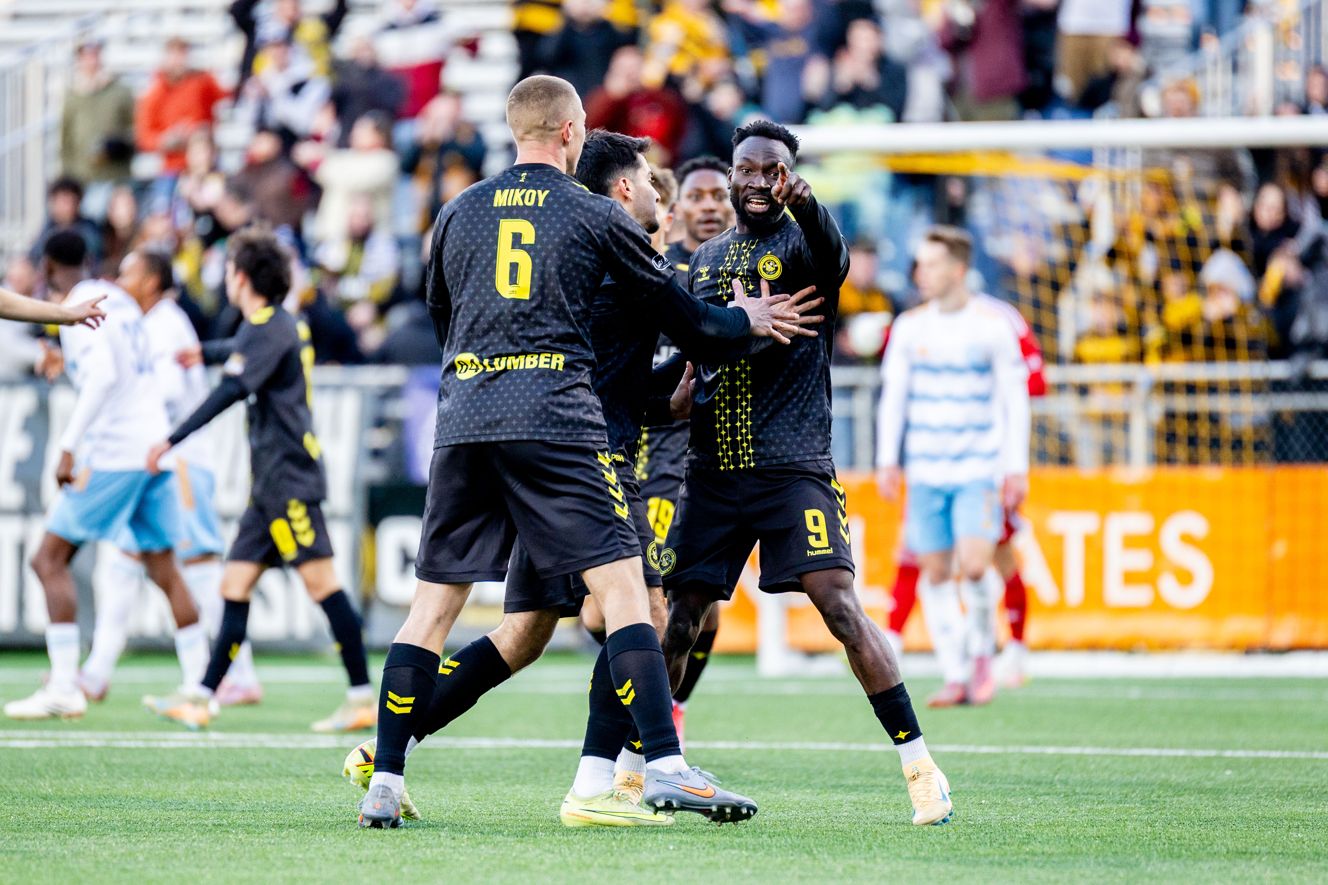 Teammates celebrate with Albert Dikwa as he points toward the bench after scoring in the Pittsburgh Riverhounds' 3-2 win over Sporting Jacksonville on March 28, 2026 at Highmark Stadium in Pittsburgh. (Photo: Chris Cowger/Riverhounds SC)