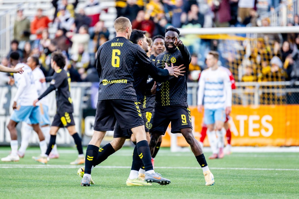Teammates celebrate with Albert Dikwa as he points toward the bench after scoring in the Pittsburgh Riverhounds' 3-2 win over Sporting Jacksonville on March 28, 2026 at Highmark Stadium in Pittsburgh. (Photo: Chris Cowger/Riverhounds SC)